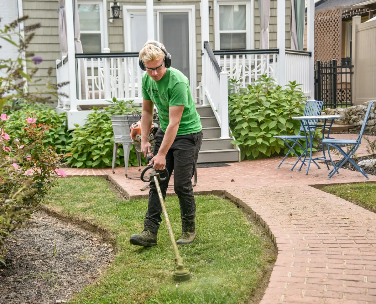 Groundwork gardener trimming lawn edges along a brick path