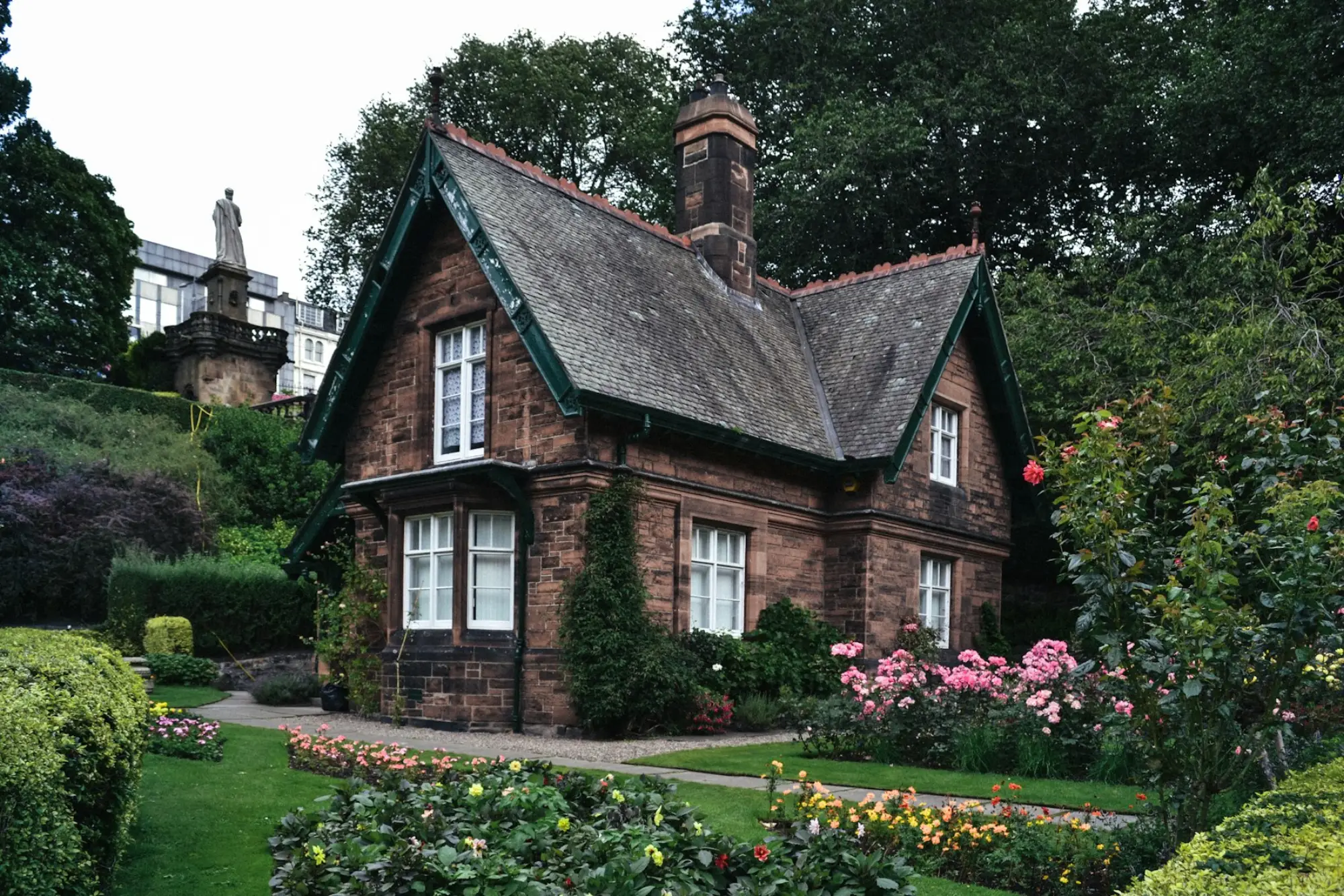 Stone cottage with a lawn, clipped hedges and flowering borders
