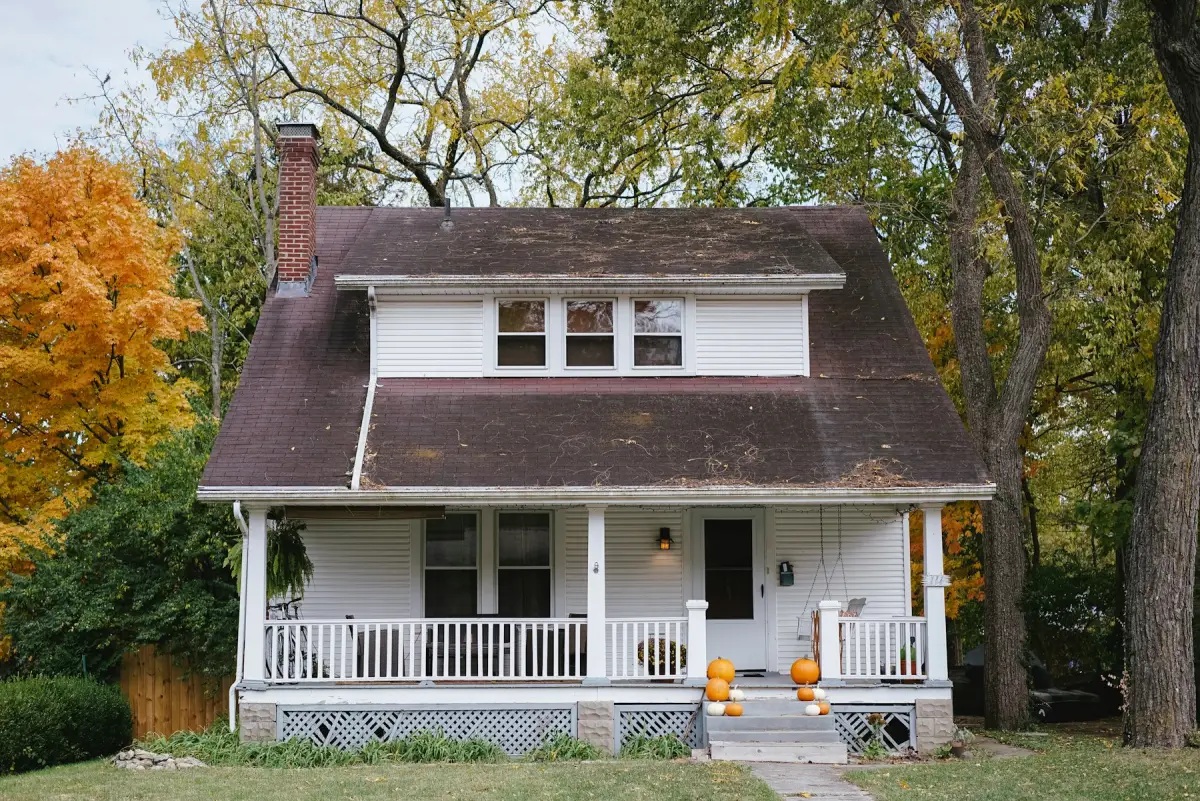 White craftsman bungalow among autumn trees